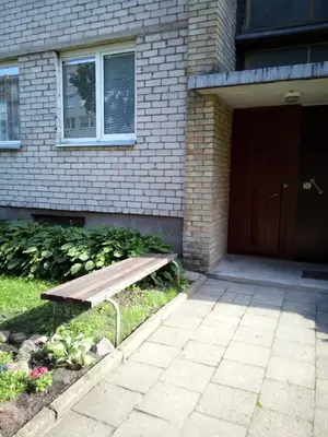 a wooden bench sitting in front of a building at Nakvynė Anykščių centre in Anykščiai