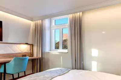 a bedroom with a bed and a desk and a window at Hotel Vilnia in Vilnius