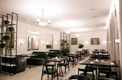 a dining room with tables and green chairs at Šaulys in Šiauliai