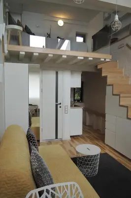 a living room with a couch and a staircase at Jolie Apartments in Kaunas