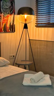 a lamp sitting next to a bed with a white towel at Modern and spacious loft type apartment 8 with free private parking by 