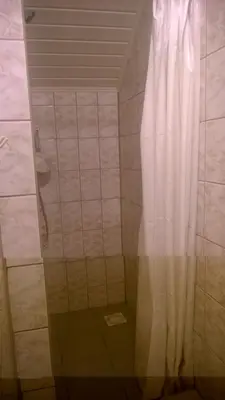 a shower with a white curtain in a bathroom at Geltona in Šiauliai