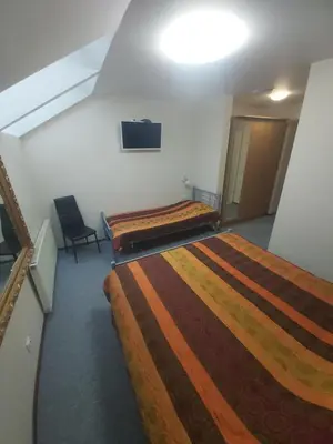 a room with two beds and a tv on the wall at Geltona in Šiauliai