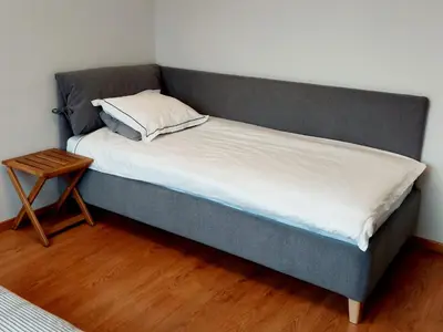 a bed with a gray headboard and a wooden table at New apartament very close to the city centre in Vilnius