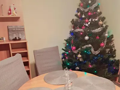 a christmas tree in the corner of a room with a table at Poilsis Pas Tada in Druskininkai