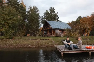 two people sitting on a dock in front of a house at House of Sparkles in Elektrėnai