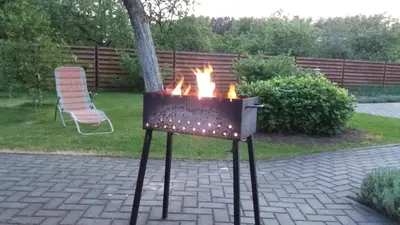 a barbecue grill with flames in a backyard at Verkių Namelis in Vilnius