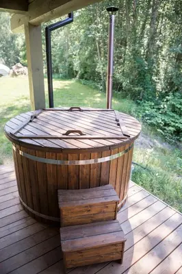 a wooden hot tub sitting on a wooden deck at Sodyba Namelis medyje Anykščiuose in Anykščiai