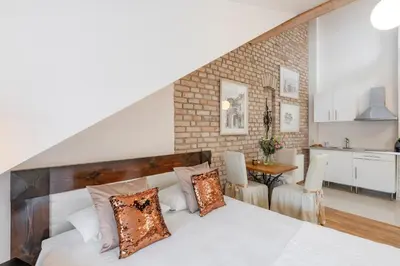 a bedroom with a white bed and a kitchen at Stepono apartments in Vilnius