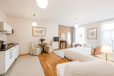 a white room with two beds and a kitchen at Stepono apartments in Vilnius