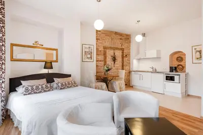 a white bedroom with a bed and a kitchen at Stepono apartments in Vilnius