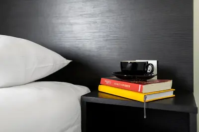 a stack of books and a cup on a table next to a bed at Comfort Hotel LT - Rock 'n' Roll Vilnius in Vilnius