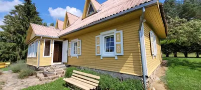 a yellow house with a bench in front of it at Sodyba Dubinga in Molėtai