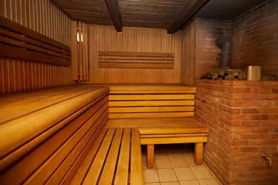 a sauna with a wooden bench and a brick wall at Sodyba Dubinga in Molėtai