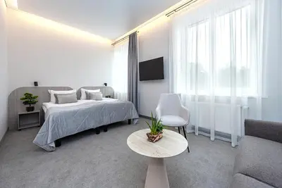 a white bedroom with a bed and a couch at Nykščio Namai & SPA in Anykščiai