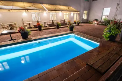 a swimming pool with blue water in a building at Nykščio Namai & SPA in Anykščiai