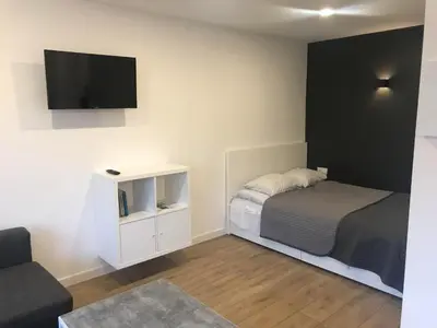 a small bedroom with a bed and a tv on the wall at Biliūno studio in Anykščiai
