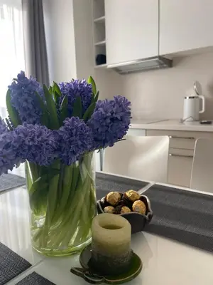a vase with purple flowers and a candle on a counter at New apartments for your stay in Vilnius in Vilnius