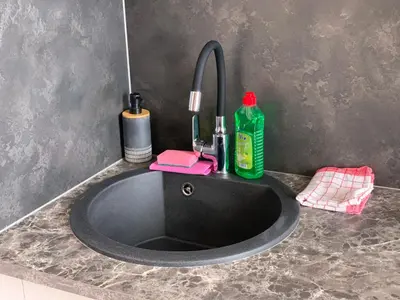 a black bathroom sink with a green bottle of soap at Sweet Apartments in Šiauliai