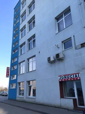a tall building with a sign on the side of it at Motelis Jonučiai in Garliava