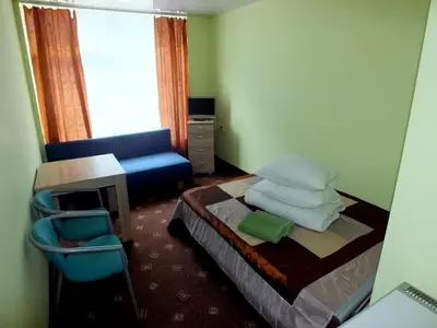 a small bedroom with a bed and a blue couch at Motelis Jonučiai in Garliava
