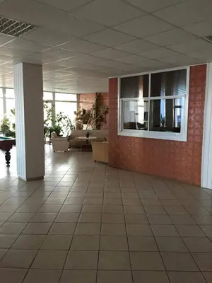 a living room with a couch and a wall of windows at Motelis Jonučiai in Garliava