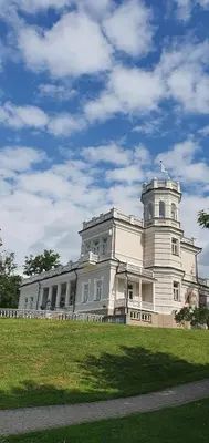a large white building on top of a grass field at Relax Inn Druskininkai in Druskininkai