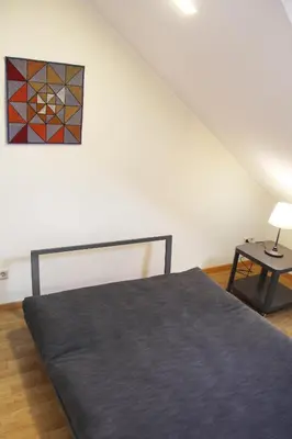 a bedroom with a bed and a table and a painting at Nemunas Street Apartment in Kaunas