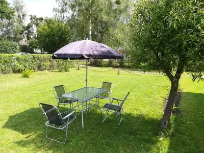 a table and chairs under an umbrella in a yard at Atostogų namai in Druskininkai
