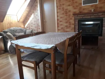 a dining room table with chairs and a fireplace at Alyvos in Ignalina