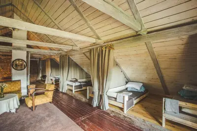 an attic room with two beds and a table at Pagulbis - Tavo namai in Klabiniai