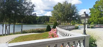 a fence next to a lake with a street light and flowers at Chocolate Apart in Druskininkai