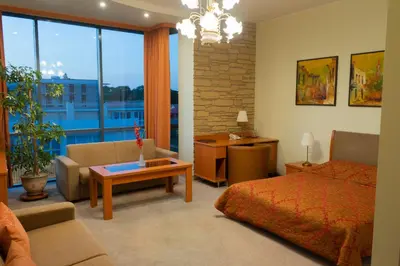 a bedroom with a bed and a living room at Hotel Vaidila in Alytus