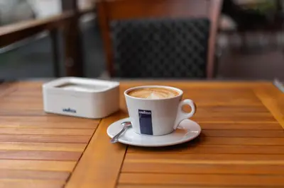 a cup of coffee sitting on a wooden table at Hotel Vaidila in Alytus