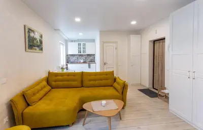 a living room with a yellow couch and a table at Classic Old Town Apartment in Druskininkai