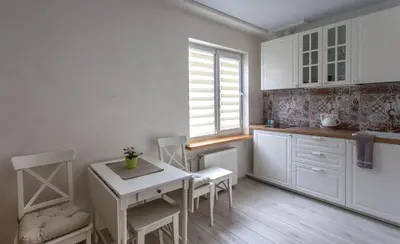 a kitchen with white cabinets and a table and chairs at Classic Old Town Apartment in Druskininkai