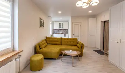 a living room with a yellow couch and a table at Classic Old Town Apartment in Druskininkai