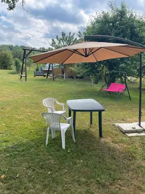 a picnic table and two chairs under an umbrella at Česlovos sodyba in Zarasai