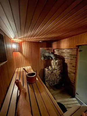 a persons hand in a sauna with a fireplace at Escape of city in Pabiržė