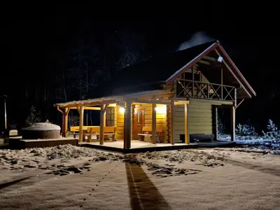 a small cabin with a lit up porch at night at Escape of city in Pabiržė
