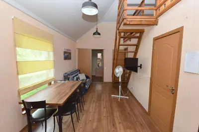 a room with a table and chairs and a staircase at Vasarnamis Zarasuose in Zarasai