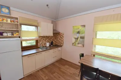 a kitchen with white cabinets and a wooden table at Vasarnamis Zarasuose in Zarasai