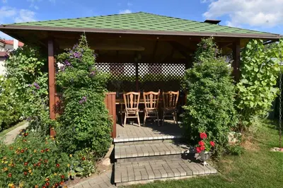 a gazebo with chairs and flowers in a garden at Vasarnamis Zarasuose in Zarasai