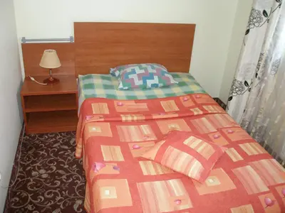 a bedroom with a bed with a red and green blanket at Motel Paradise in Vilnius