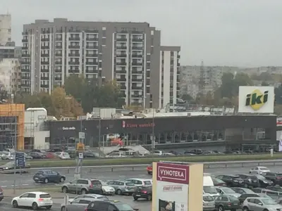 a parking lot with cars parked in front of a large building at Motel Paradise in Vilnius