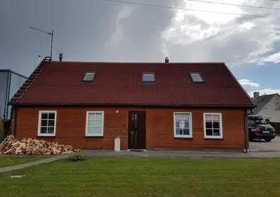 a house with a red roof and a pile of logs at Vila House in the city center of Ukmerge in Ukmergė