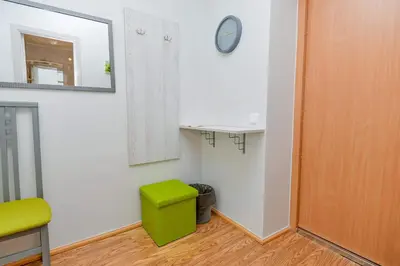 a room with a green stool and a clock on a wall at Guest House Simona in Lazdijai