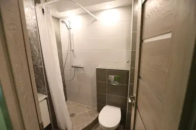 a small bathroom with a toilet and a shower at Modern & Homely Apartment - FREE PARKING - NETFLIX in Kaunas