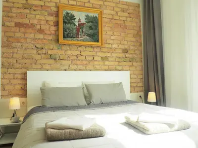a bedroom with a white bed with a brick wall at Emi apartment in Vilnius