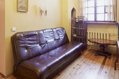 a brown leather couch in a living room with a table at Cozy Apartment in Gothic style house in the Heart of the Old Town in Vilnius